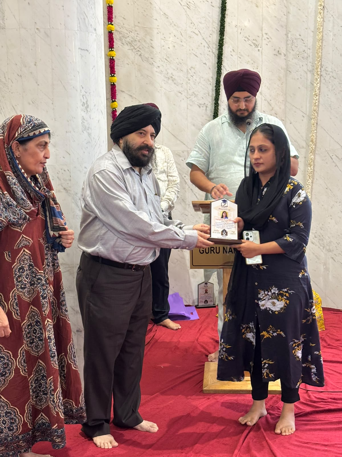 VPCF trustees felicitating a student with a Student Achievement Award plaque